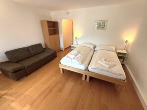Ein Schlafzimmer mit einem hölzernen Bett, einer Couch, einem Kleiderschrank und einem Nachttisch mit Lampe.