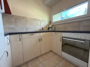 A kitchen with light-colored cabinets, a countertop, a coffee maker, and an oven. - Fortuna 113 # 2-bed apartment, Dusche, WC 2-Bettwohnung, Dusche, WC by Interhome (Leukerbad)