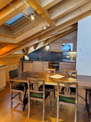 A kitchen with wooden beams, a dining table, chairs, and a view of the outdoors. - Edelweiss B 41 # 4-bed apartment, Dusche und Bad, WC by Interhome (Leukerbad)