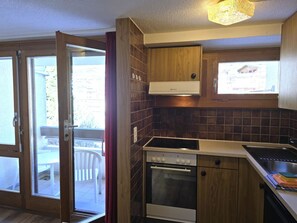 A compact kitchen with a stove, oven, and a window above the sink. - Fortuna 316 # 5-bed apartment, Dusche, WC 5-Bettwohnung, Dusche, WC by Interhome (Leukerbad)