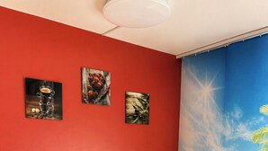 Ein Essbereich mit roter Wand, einem Tisch mit weißer Tischdecke, vier Stühlen und einer Vase mit Tulpen.