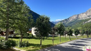 Eine Wohnstraße mit Häusern, Bäumen und einem Berg im Hintergrund.