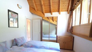 Een slaapkamer met een bed, een kledingkast en een deur naar een andere kamer.