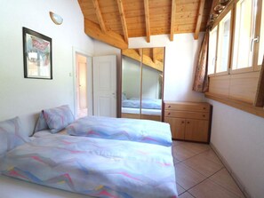 A bedroom with a bed, a wardrobe, and a door leading to another room. - Bergkristall Leukerbad # 4-bed apartment, Dusche, WC by Interhome (Leukerbad)