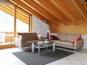 A modern living room with a glass coffee table, beige sofa, and a wooden ceiling. - Bergkristall Leukerbad # 4-bed apartment, Dusche, WC by Interhome (Leukerbad)