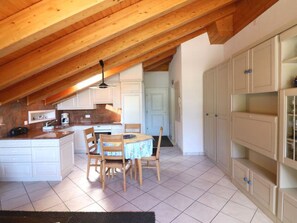 A kitchen with wooden beams, white cabinets, a dining table with chairs, and a tiled floor. - Bergkristall Leukerbad # 4-bed apartment, Dusche, WC by Interhome (Leukerbad)