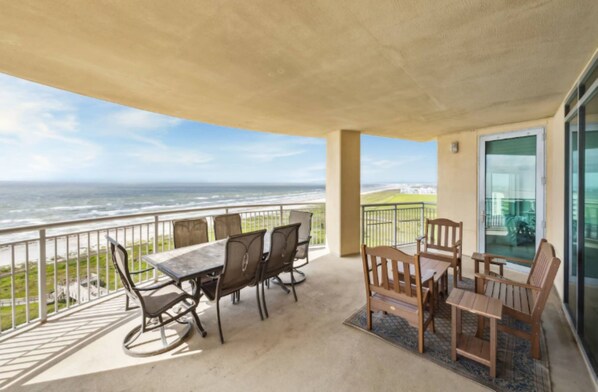 A balcony with a table and chairs, overlooking a coastal view. - Palisade Palms Beach High Rise (Galveston)
