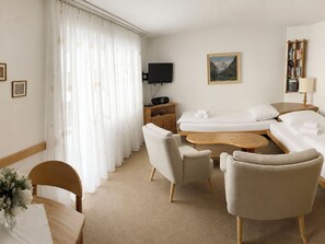 A hotel room with a sofa, two armchairs, a coffee table, a TV, a painting, a bookshelf, and a lamp. - Majesta Leukerbad # 2-bed apartment, Dusche, WC by Interhome (Leukerbad)