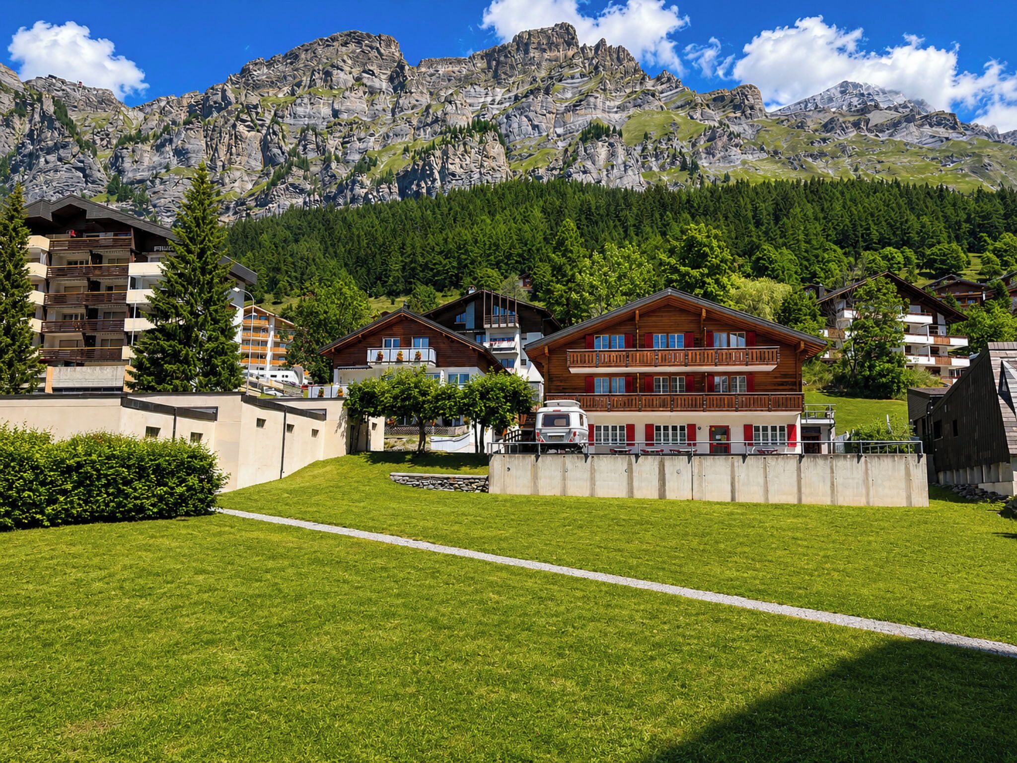 Ein Bergresort mit Chaletgebäuden, einem gepflegten Rasen und Blick auf schroffe Berge.