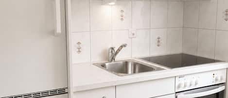 A kitchen with white cabinets, a stainless steel sink, and a built-in oven.