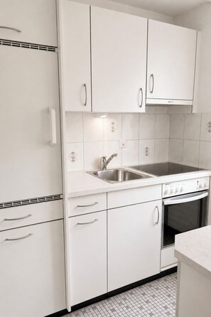 A kitchen with white cabinets, a stainless steel sink, and a built-in oven. - Majesta Leukerbad # 2-bed apartment, Dusche, WC by Interhome (Leukerbad)