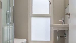 A bathroom with a toilet, a window, a glass shower enclosure, and a sink with a faucet. - 3-guest Oasis With Scenic Terrace (Madrid)
