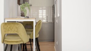A modern kitchen with a white countertop, two chairs, a potted plant, and a window with blinds. - 3-guest Oasis With Scenic Terrace (Madrid)
