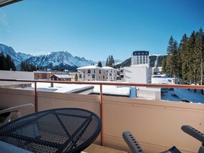 A balcony with a table and chairs, overlooking a snowy mountain landscape and buildings. - Paradies 507 Appartement/Fewo,  , 2-Bettwohnung by Interhome (Arosa)