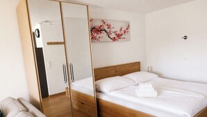 Quarto com cama de madeira, guarda-roupa com espelho e um quadro na parede.