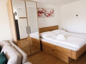 Ein Schlafzimmer mit einem hölzernen Bett, einem Schrank mit Spiegel und einem Gemälde an der Wand.
