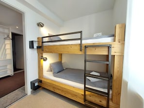 A bunk bed with a ladder, a bedside table, and a wall-mounted lamp. - Viktoria A39 by Arosa Holiday Appartement/Fewo, Dusche, WC, 6-Bettwohnung by Interhome (Arosa)
