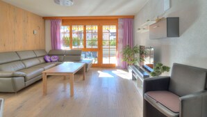 Un salon avec un canapé, une table, une chaise, un téléviseur et une plante.