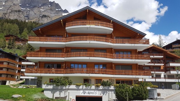 Un hôtel à plusieurs étages, doté de balcons, d’un garage et situé dans un cadre montagneux.