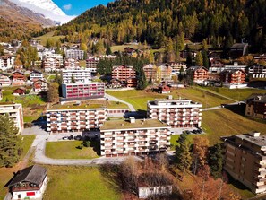 A cluster of multi-story buildings with balconies, surrounded by a mountainous landscape. - Valère Leukerbad # 2-bed apartment, Dusche, WC by Interhome (Leukerbad)