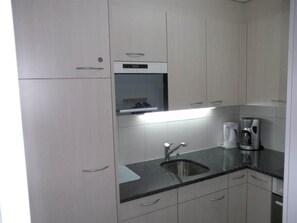 A modern kitchen with a built-in oven, a stainless steel sink, and a coffee maker. - Valère Leukerbad # 2-bed apartment, Dusche, WC by Interhome (Leukerbad)