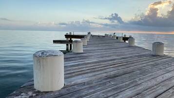 A wooden pier extending into calm water with a bench and bollards.