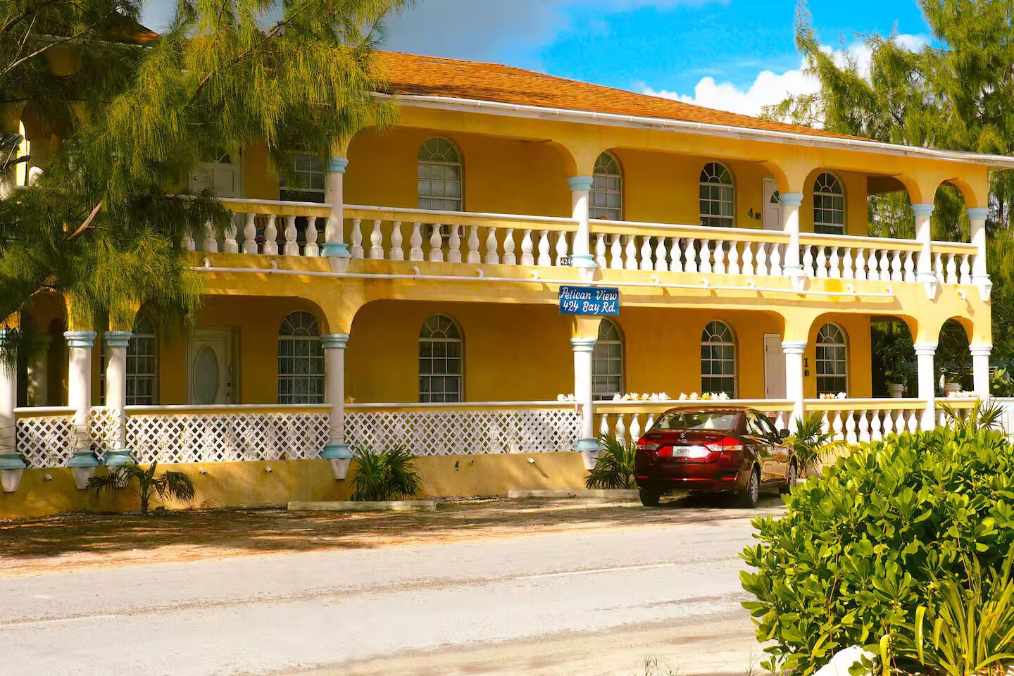A yellow building with a balcony, columns, and a street sign.
