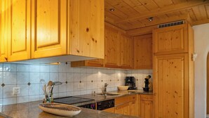 Una cocina con armarios de madera, encimera de granito, cafetera y lavavajillas.