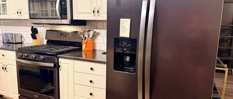 A kitchen with stainless steel appliances, including a refrigerator, microwave, and oven.