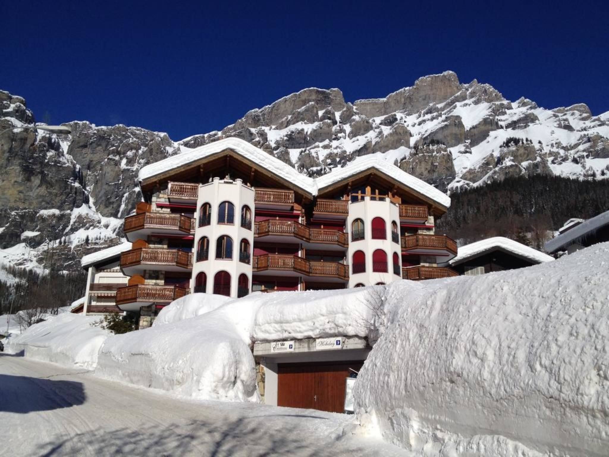 Ein mehrstöckiges Hotel mit Balkonen vor einer Bergkulisse.