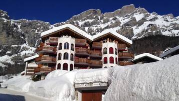 Ein mehrstöckiges Hotel mit Balkonen vor einer Bergkulisse.