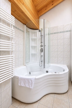 A modern bathroom with a freestanding bathtub, a glass-enclosed shower, and a white towel on the tub. - Residenz Château # 3-bed apartment, Bad, WC by Interhome (Leukerbad)