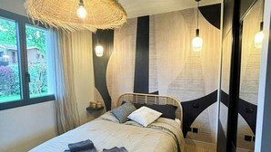 A modern bedroom with a bed, bedside tables, a large woven light fixture, and a view through the window. - Villa with pool near Bassin d'Arcachon (La Teste de Buch)