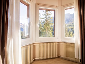 Habitación de esquina con ventanal que da a un bosque y montañas.