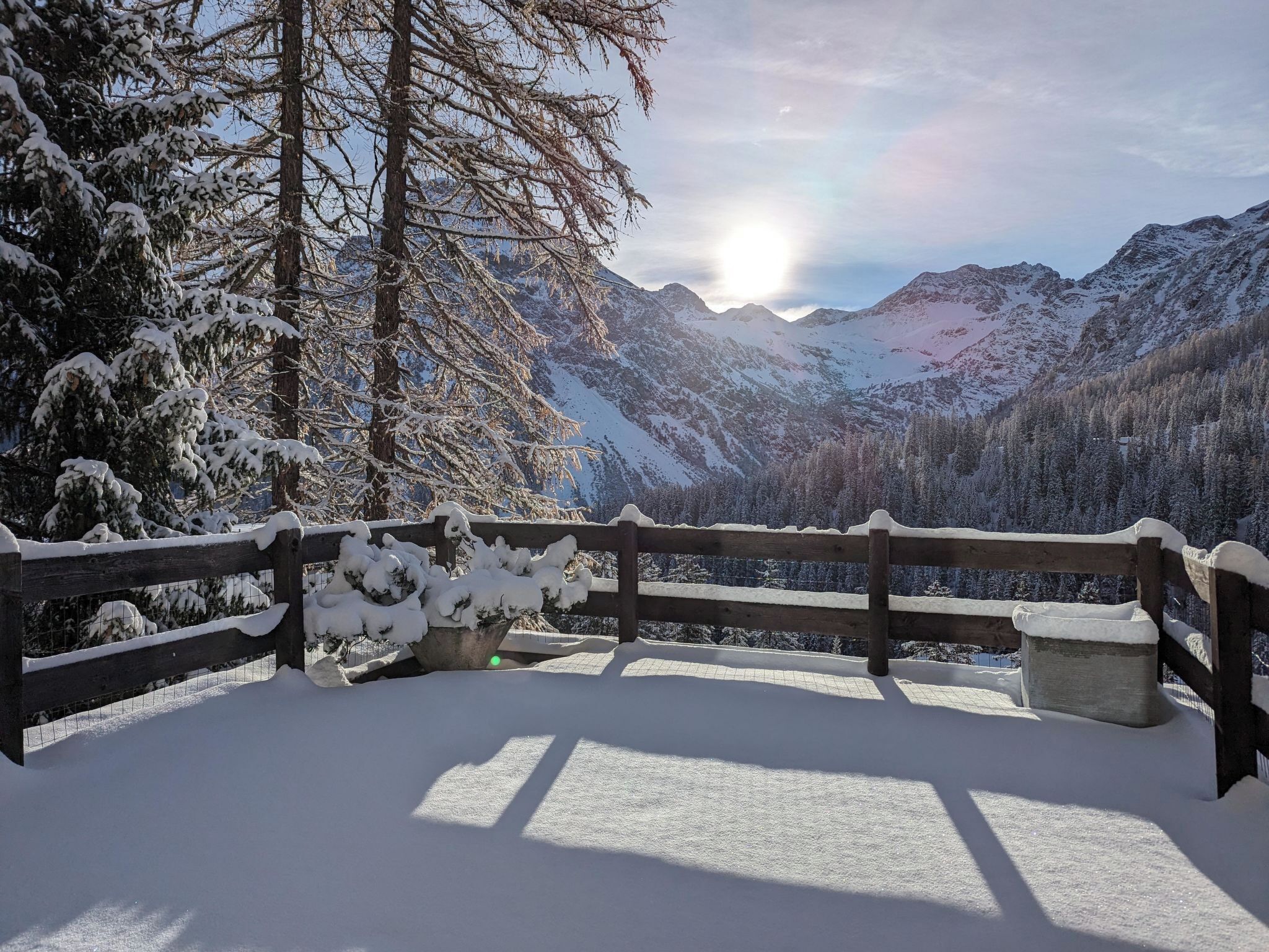 A snow-covered landscape with a wooden fence and a bench.