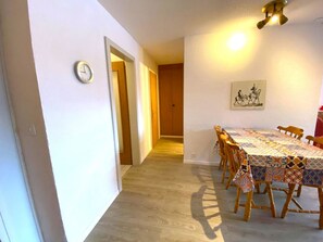 A dining area with a table set for six, wooden chairs, a clock on the wall, and a ceiling light fixture. - Salute 108 # 4-bed apartment, Dusche, WC 4-Bettwohnung, Dusche, WC by Interhome (Leukerbad)