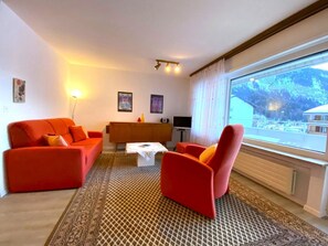 A living room with a sofa, armchair, and a coffee table. There is a TV and a cabinet in the room. - Salute 108 # 4-bed apartment, Dusche, WC 4-Bettwohnung, Dusche, WC by Interhome (Leukerbad)