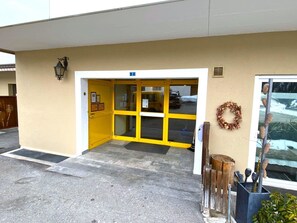 A building entrance with a yellow door, a sign indicating room number 2, and a wreath on the right. - Salute 108 # 4-bed apartment, Dusche, WC 4-Bettwohnung, Dusche, WC by Interhome (Leukerbad)