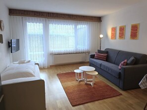A hotel room with a bed, a sofa, a small table, and a floor lamp. - Leuca 24 # 2-bed apartment, Dusche, WC 2-Bettwohnung, Dusche, WC by Interhome (Leukerbad)