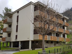 Um edifício residencial com vários andares, varandas, base de pedra e uma placa com o nome 'leuca'.