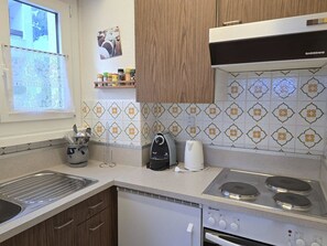A modern kitchen with a built-in oven, a coffee maker, and a kettle on the countertop. - Leuca 24 # 2-bed apartment, Dusche, WC 2-Bettwohnung, Dusche, WC by Interhome (Leukerbad)