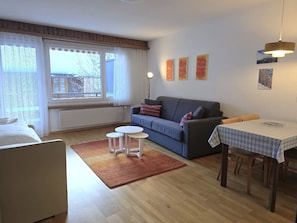 A furnished room with a sofa, a small table, a coffee table, and a window with curtains. - Leuca 24 # 2-bed apartment, Dusche, WC 2-Bettwohnung, Dusche, WC by Interhome (Leukerbad)