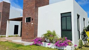 A modern building with a brick chimney, white walls, and a window.