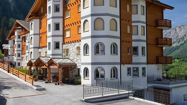 Ett hotell med flera våningar, en reception, balkonger och en bergig bakgrund.