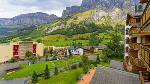 Ett bostadsområde med utsikt över berg, en röd byggnad och ett trähus med en balkong.