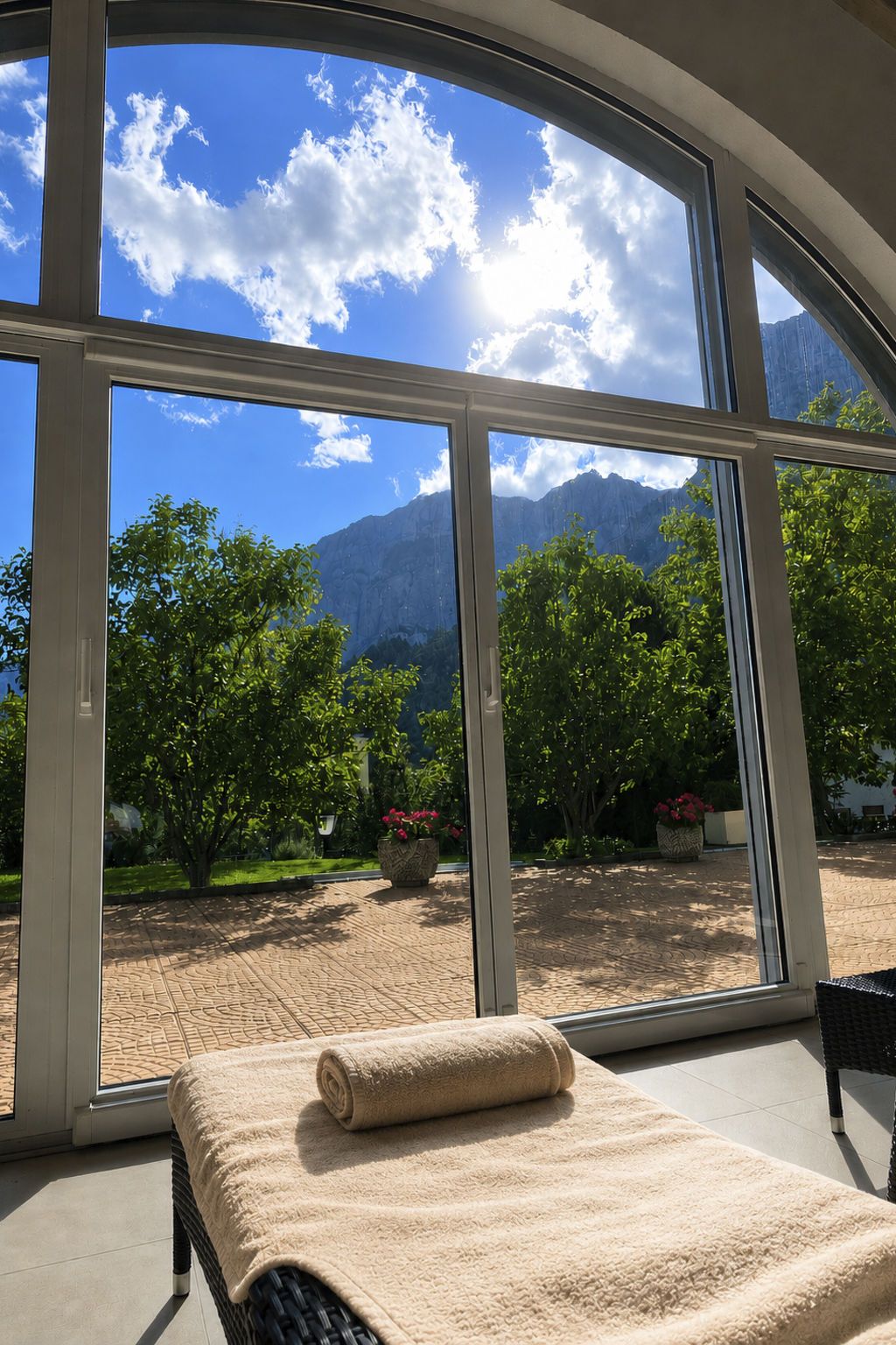 A room with a large window offering a view of a mountainous landscape and a garden.