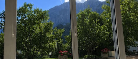 A room with a large window offering a view of a mountainous landscape and a garden.