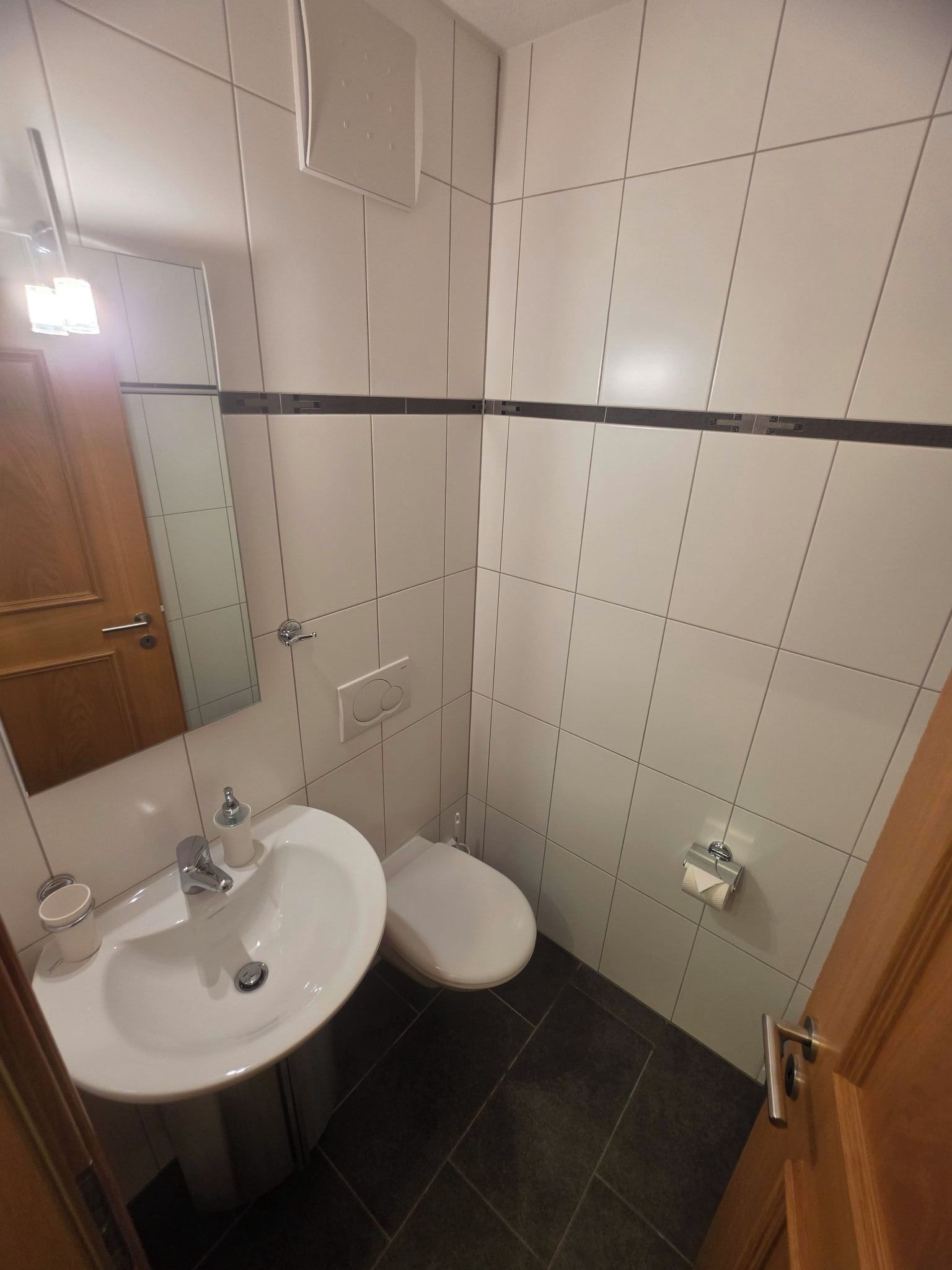 Et badeværelse med en hvid vask, toilet og spejl.