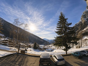 Ein Parkplatz mit Autos, Bergen im Hintergrund und blauem Himmel.