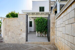 A stone wall entrance to a building with a paved pathway leading to a door.